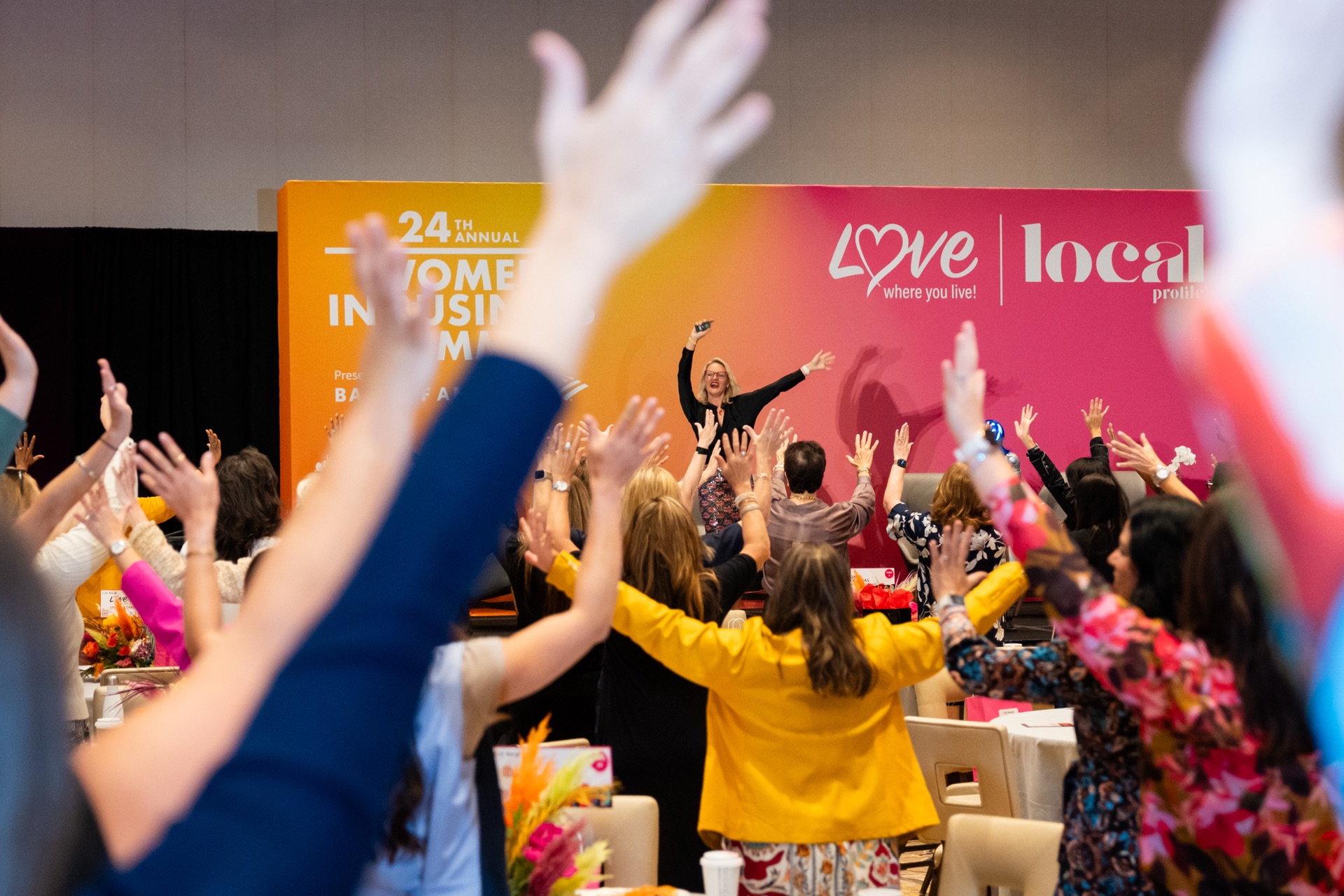Rebecca Silvestri on stage with audience members raising their hands in an energetic moment